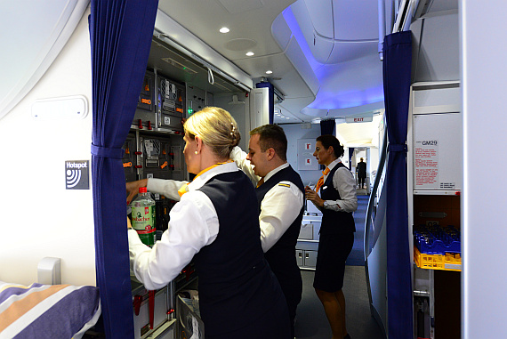  Busy Lufthansa male and female flight-attendants in crowded galley.